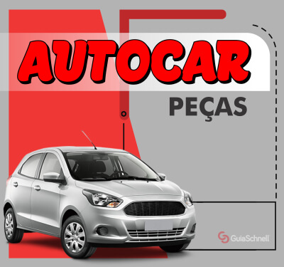 A imagem promocional destaca um carro Ford Ka cinza prateado, visto da frente e de lado. O fundo é dividido, com uma grande forma em vermelho no lado esquerdo e um fundo cinza no lado direito. Formas geométricas em vermelho escuro e uma faixa branca com bordas arredondadas emolduram o logotipo. O nome AUTOCAR é exibido em letras grandes e vermelhas, com a palavra PEÇAS em letras pretas menores logo abaixo. O logotipo do GuiaSchnell está no canto inferior direito