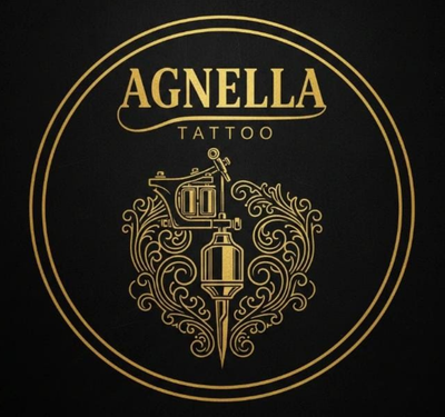 Logo dourado circular da Agnella Tattoo sobre fundo preto elegante, com tipografia em destaque e ornamentos decorativos em estilo filigrana, representando máquina de tatuagem estilizada.
